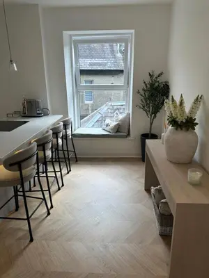 a kitchen with a counter and bar stools and a window at Luxury High Street Apartment in Moffat