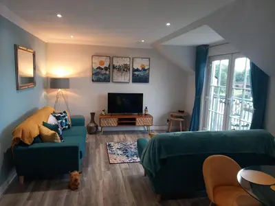 a living room with a green couch and a tv at Idyllic Waterside Penthouse in Callander