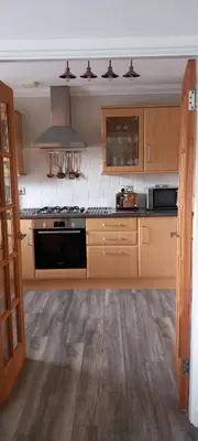 a kitchen with wooden cabinets and a stove top oven at Idyllic Waterside Penthouse in Callander