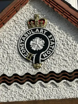 a sign on the side of a building with a flower on it at Peel House Bed and Breakfast in Girvan