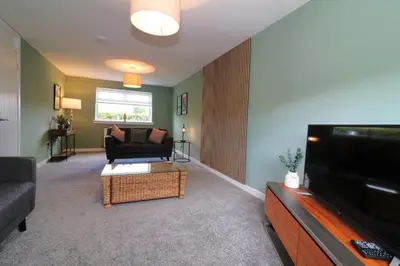 a living room with a couch and a flat screen tv at Signature - Martin House in Old Monkland