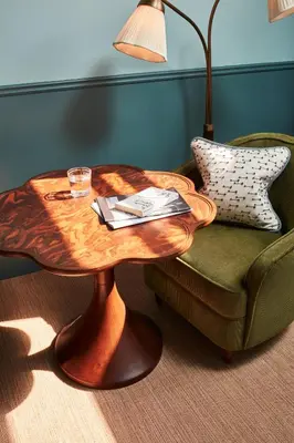 a wooden coffee table in front of a chair with a lamp at The Hoxton, Edinburgh in Edinburgh