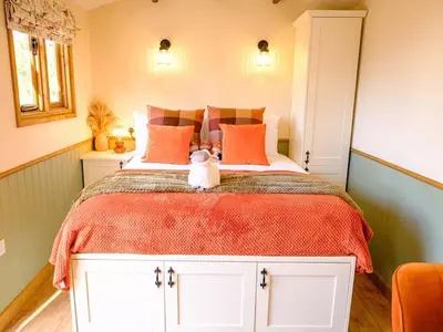 a bedroom with a large bed with orange pillows at Lintmill Lodges - Heather Shepherds Hut in Sorn