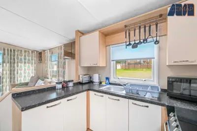 a kitchen with white cabinets and a sink and a window at Loch Lomond - Ard Lui Lodge in Ardlui