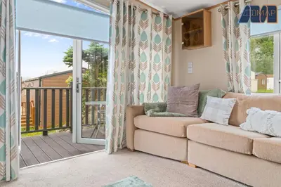 a living room with a couch and a balcony at Loch Lomond - Ard Lui Lodge in Ardlui