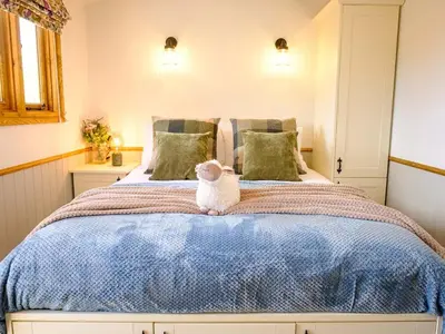 a bed with a teddy bear sitting on top of it at Lintmill Lodges - Bluebell Shepherds Hut in Sorn