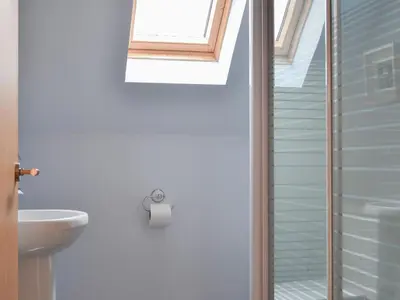 a bathroom with a shower and a toilet and a window at Pine Marten Cottage in Ballachulish