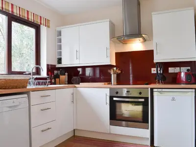 a kitchen with white cabinets and an oven at Pine Marten Cottage in Ballachulish