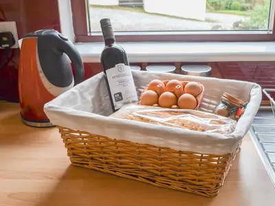 a basket with a bottle of wine and eggs at Pine Marten Cottage in Ballachulish