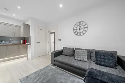 a living room with a couch and a clock on the wall at Upper Grove 2 Bedroom Apartment - Edinburgh in Edinburgh