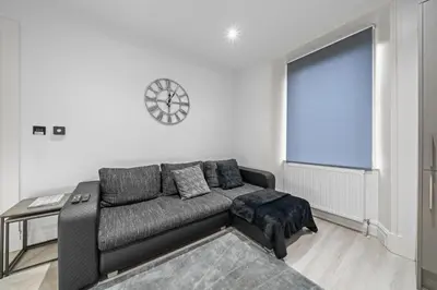 a living room with a couch and a clock on the wall at Upper Grove 2 Bedroom Apartment - Edinburgh in Edinburgh