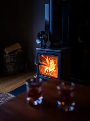a wood stove with a fire in it in a room at Jura - The Rusty Hut in Craighouse