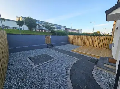 a backyard with a fence and a wooden patio at Ardenslate House in Kirn