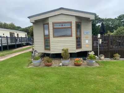 a tiny house in a yard with potted plants at Turnberry Holiday Park in Turnberry