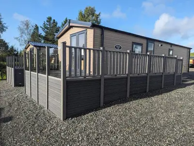 a small house with a wooden fence at Newton Stewart - Lodge - Sleeps 4 - Garden in Bargrennan