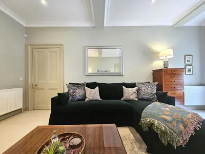 a living room with a black couch and a table at Edinburgh Elegant 1-Bedroom City Apartment in Edinburgh