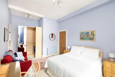 a bedroom with a white bed and a red chair at Charming 1-Bedroom Edinburgh City Getaway in Edinburgh