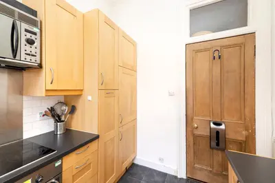 a kitchen with wooden cabinets and a microwave at Charming 1-Bedroom Edinburgh City Getaway in Edinburgh