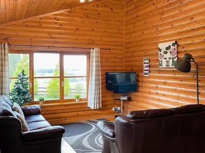 a living room with two couches and a tv in a log cabin at Ashknowe Log Cabin - S4590 in Glenfarg