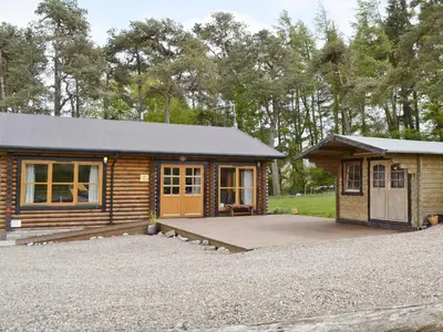 a log cabin with a porch and a small building at Ashknowe Log Cabin - S4590 in Glenfarg