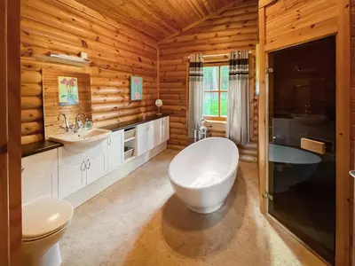 a bathroom with a tub and a toilet and a sink at Ashknowe Log Cabin - S4590 in Glenfarg