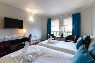 a hotel room with two beds and a flat screen tv at Glynhill Hotel & Spa near Glasgow Airport in Paisley