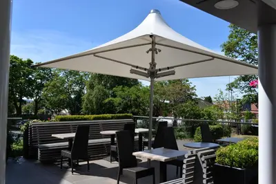 a patio with tables and chairs under a white umbrella at Glynhill Hotel & Spa near Glasgow Airport in Paisley