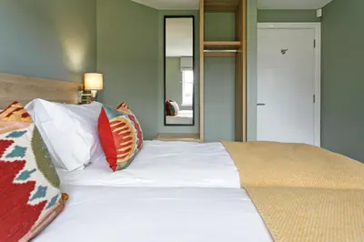 a large white bed with pillows on top of it at Troon No 1 Apartments in Troon