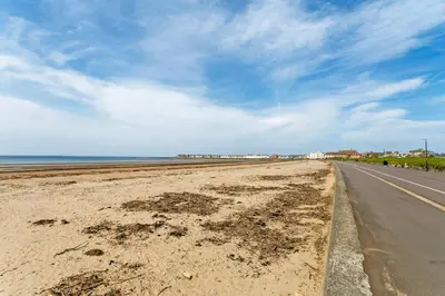 an empty road next to a beach with the ocean at Troon No 1 Apartments in Troon