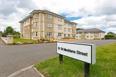 a sign in the grass in front of a building at Troon No 1 Apartments in Troon