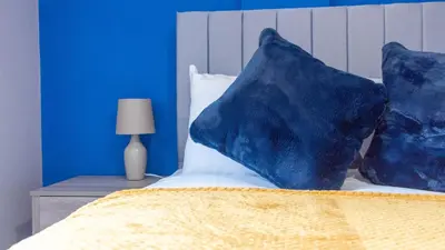 a bedroom with blue walls and a bed with blue pillows at Campsie View in Glasgow