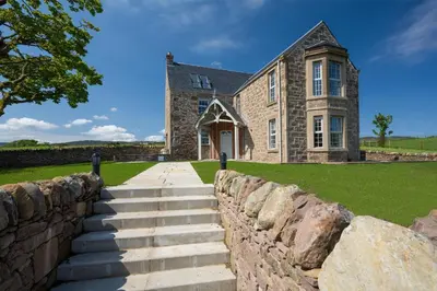 a stone house with a stone wall in front of it at Milton House in Buchanty