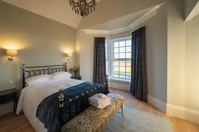 a bedroom with a bed and a large window at Milton House in Buchanty