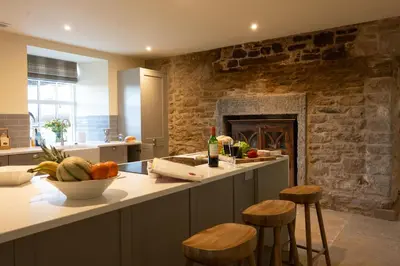 a kitchen with a counter with stools and a fireplace at Milton House in Buchanty