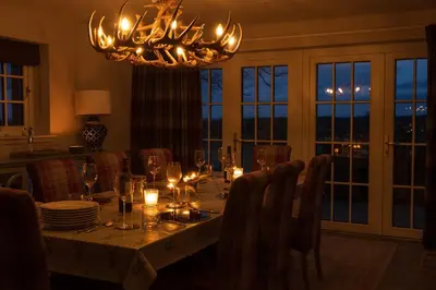 a dining room with a table with a chandelier at The Old Farmhouse in Buchanty