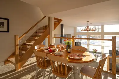 a dining room with a table and chairs and a staircase at Falcon Steading in Buchanty