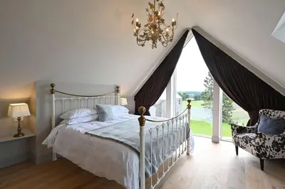 a bedroom with a bed and a chandelier and a window at Falcon Steading in Buchanty