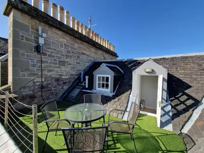 a patio with a table and chairs next to a wall at Rose Street 4 bedroom in Edinburgh