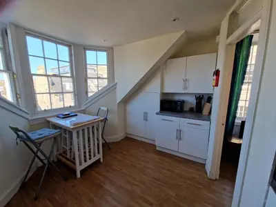 a kitchen with white cabinets and a table in a room at Rose Street 4 bedroom in Edinburgh