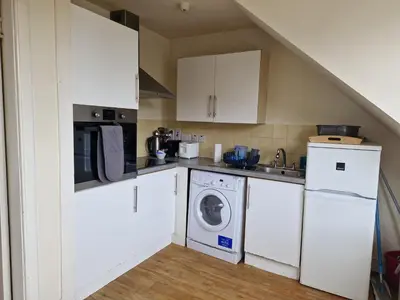 a kitchen with white cabinets and a washer and dryer at Rose Street 4 bedroom in Edinburgh