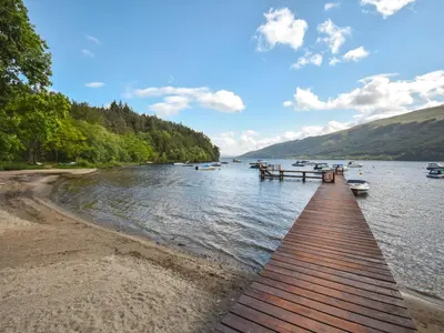 a dock on a lake with boats in the water at Lomond View Lodge in Rowardennan