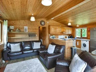 a living room with leather couches and a kitchen at Lomond View Lodge in Rowardennan