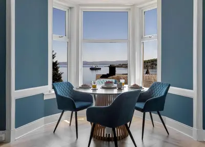 a dining room with a table and chairs and a large window at The Bayview, Rothesay, Isle of Bute in Rothesay