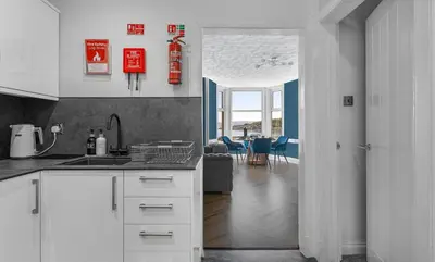 a kitchen with white cabinets and a living room at The Bayview, Rothesay, Isle of Bute in Rothesay