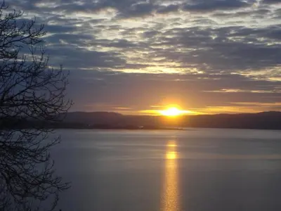 a sunset over a large body of water at The Bayview, Rothesay, Isle of Bute in Rothesay