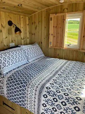 a bedroom with a bed in a wooden cabin at Wee Beach Hut Maidens in Maidens