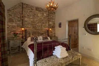 a bedroom with a bed and a stone wall at Merlin Steading with hot tub in Buchanty