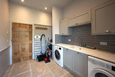 a kitchen with a sink and a washing machine at Merlin Steading with hot tub in Buchanty