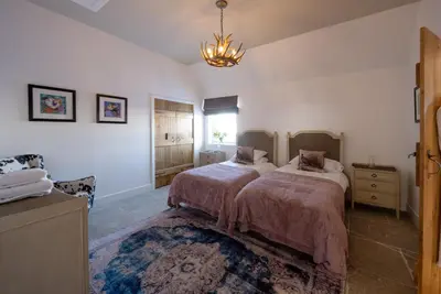 a bedroom with two beds and a chandelier at Merlin Steading with hot tub in Buchanty