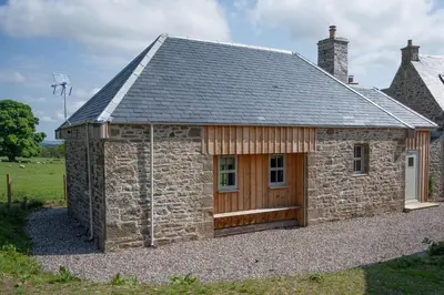 a stone house with a gambrel roof and a garage at The Bothy in Buchanty